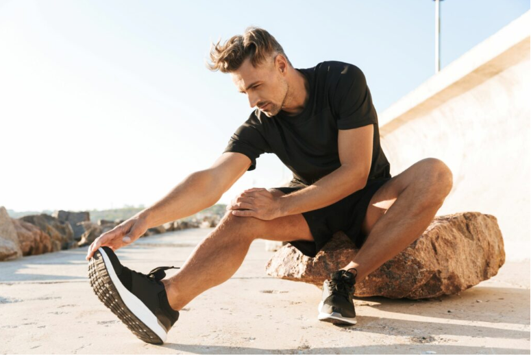 Homme s'échauffant avant le jogging portant un T-shirt noir et des chaussures de sport