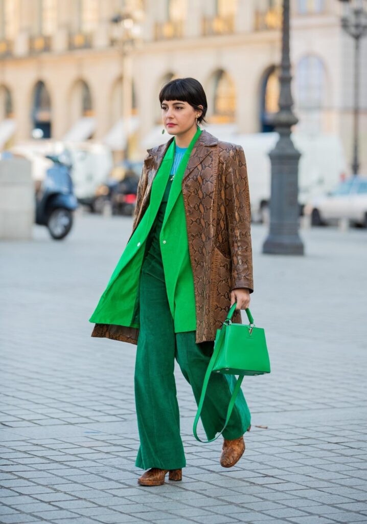 Maria Bernad en pantalon, blazer et sac à main verts, avec des bottines marron à talons blocs